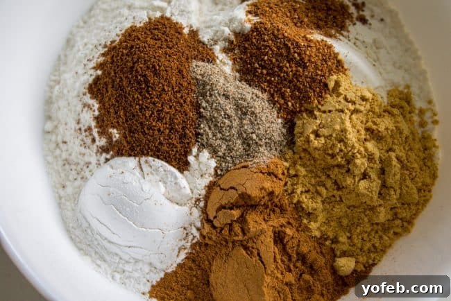 A bowl of assorted pumpkin pie spices including cinnamon, ginger, cloves, nutmeg, and cardamom.