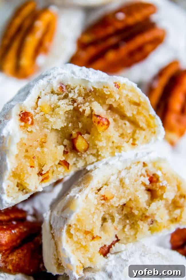 Classic Mexican Wedding Cookies (Russian Tea Cakes) with pecans and powdered sugar, an easy and festive holiday recipe. Mexican wedding cookies broken in half and stacked with pecans in the back, highlighting their crumbly, nut-filled texture.