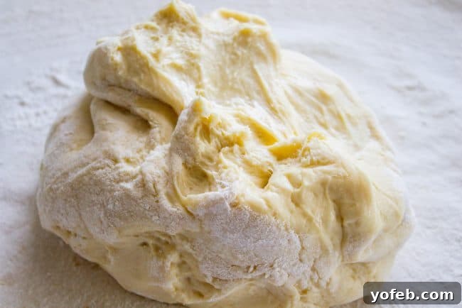 Chilled brioche dough rolled out on a floured surface, ready for the cinnamon sugar filling.