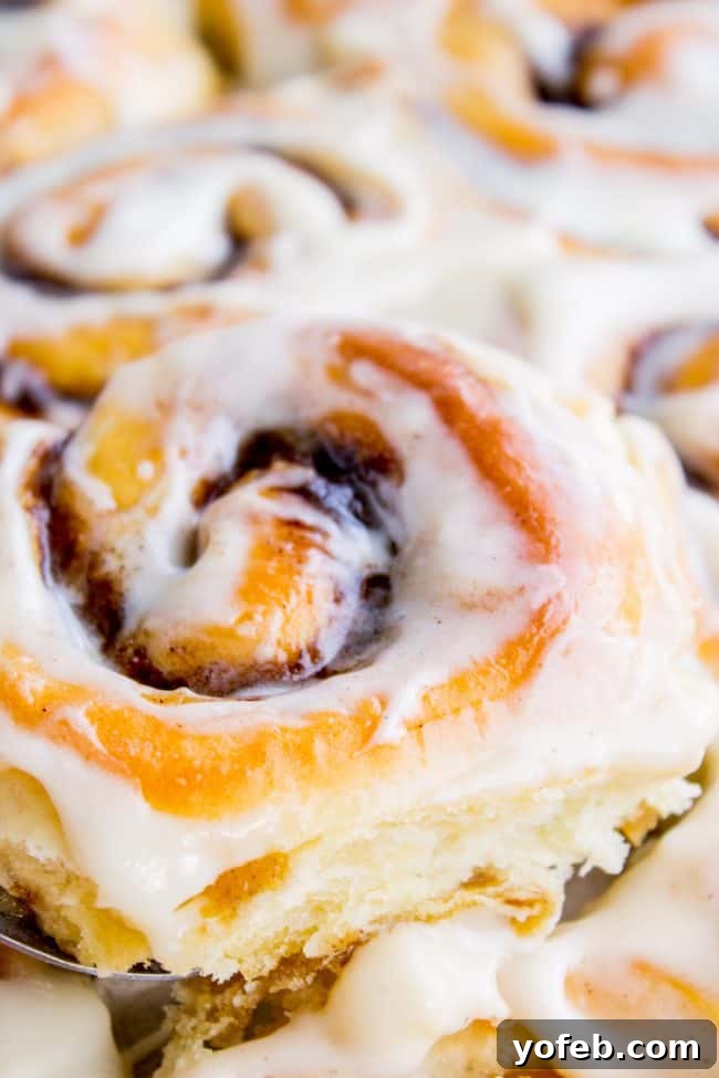 A close-up shot of a cinnamon roll generously covered in creamy white icing, highlighting its irresistible texture.