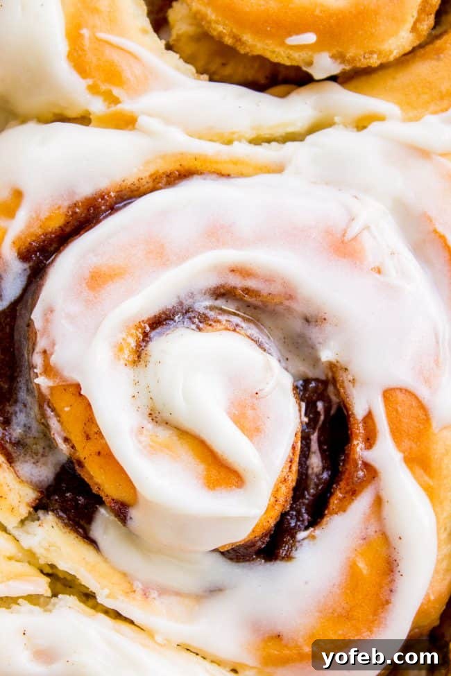 A close-up of the perfectly baked top of homemade cinnamon rolls, showing a hint of the delicious cinnamon swirl underneath.