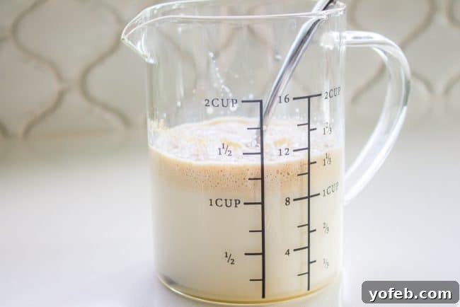 Measuring warm milk, an essential first step for activating yeast in homemade cinnamon rolls.