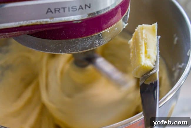 A knife with softened butter hovering over a mixing bowl, ready to be incorporated into the cinnamon roll dough.