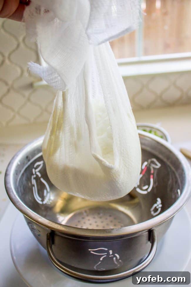 Refreshing Tzatziki with Warm Zaatar Pita Chips 5 A setup showing yogurt being strained through cheesecloth in a colander over a bowl, essential for a thick tzatziki sauce.