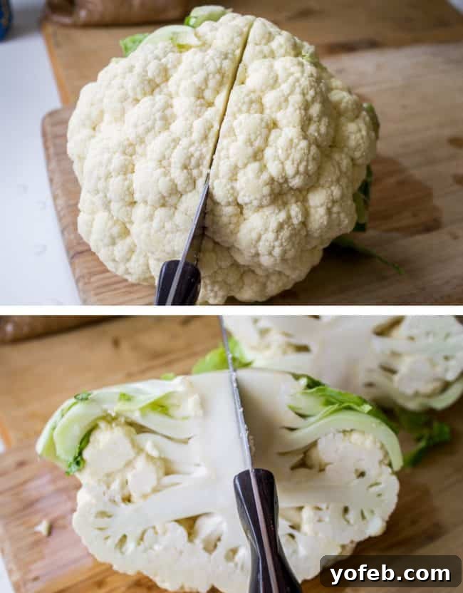 A large head of cauliflower being cut in half on a wooden cutting board.