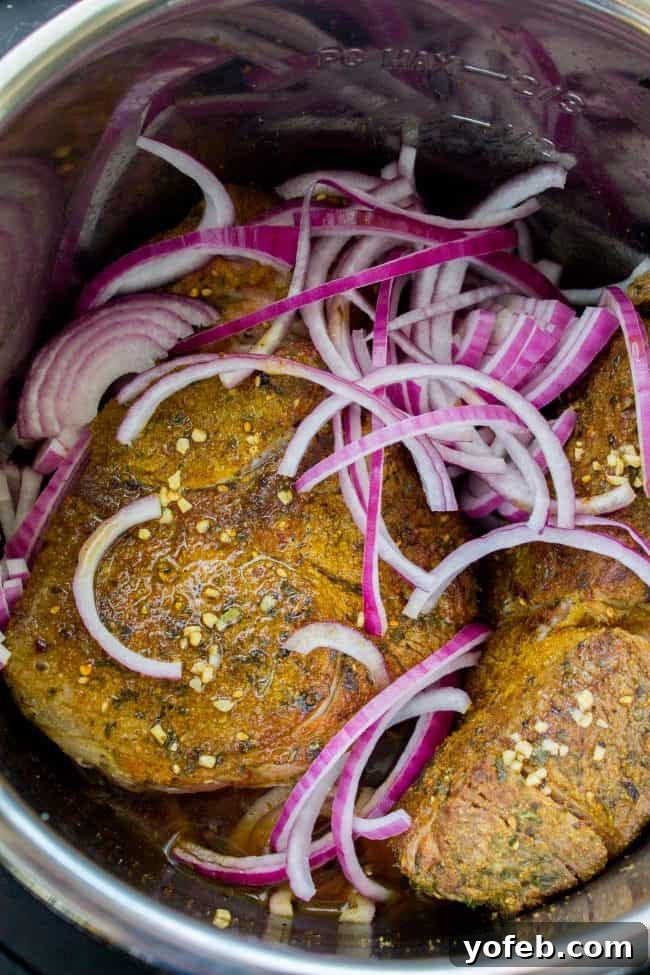 Spiced beef roast and red onions ready for Instant Pot Gyro cooking. A robust beef roast, beautifully browned and coated with aromatic spices, nestled in the Instant Pot with savory sliced red onions.