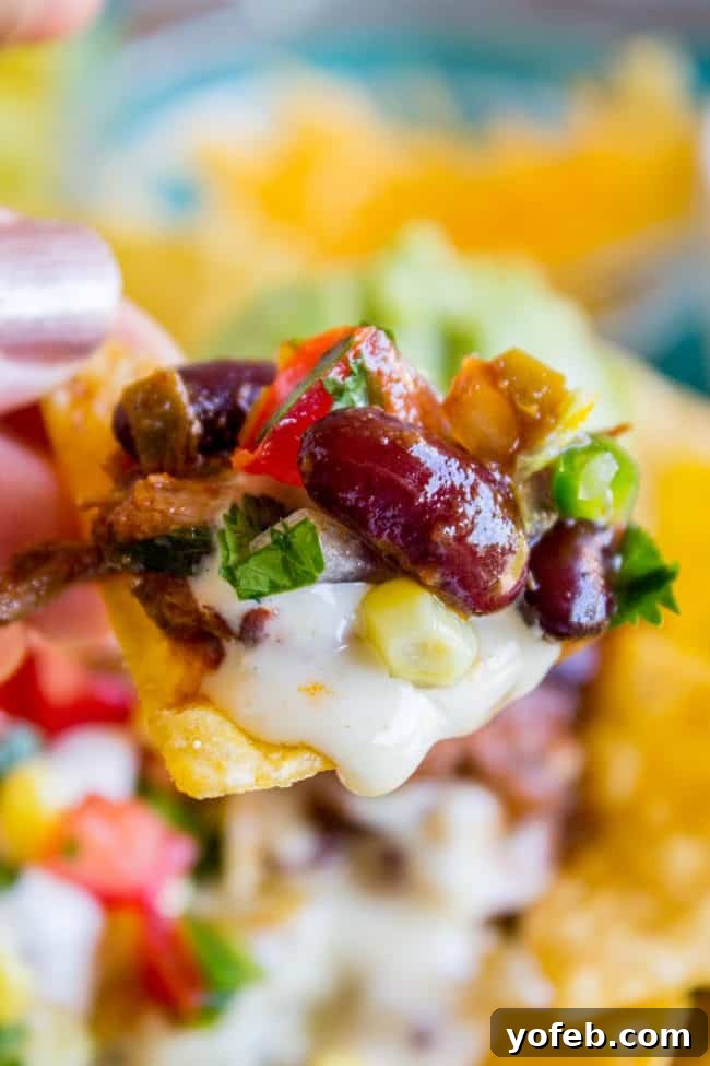 Stacked Chili Nachos with Molten Queso and Fresh Guacamole 4 Loaded nachos recipe featuring chili, queso, and fresh garnishes, ready to be served.