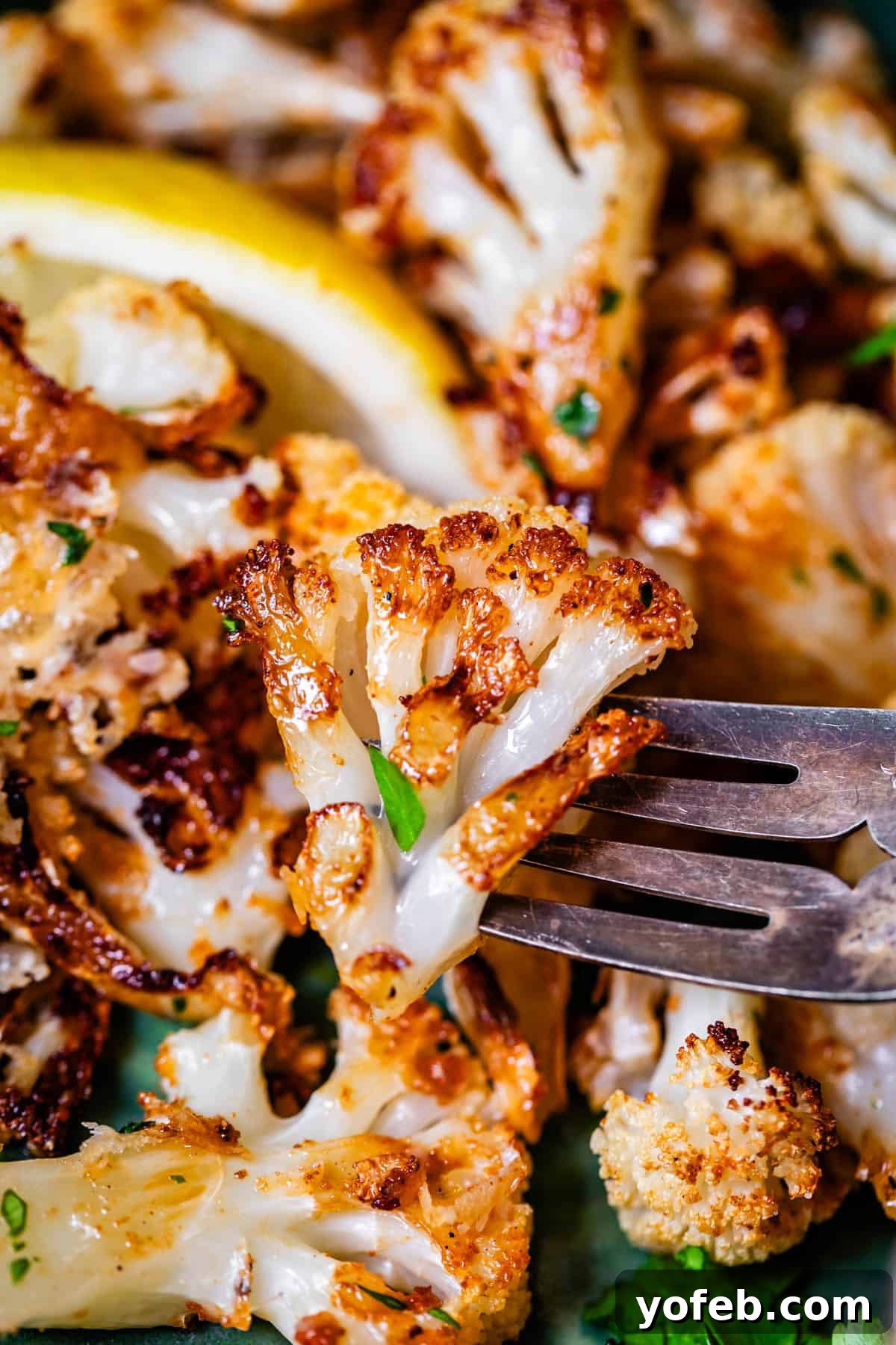 Perfectly Golden and Crispy Roasted Cauliflower 19 fork holding up a pierced floret of golden roasted cauliflower.