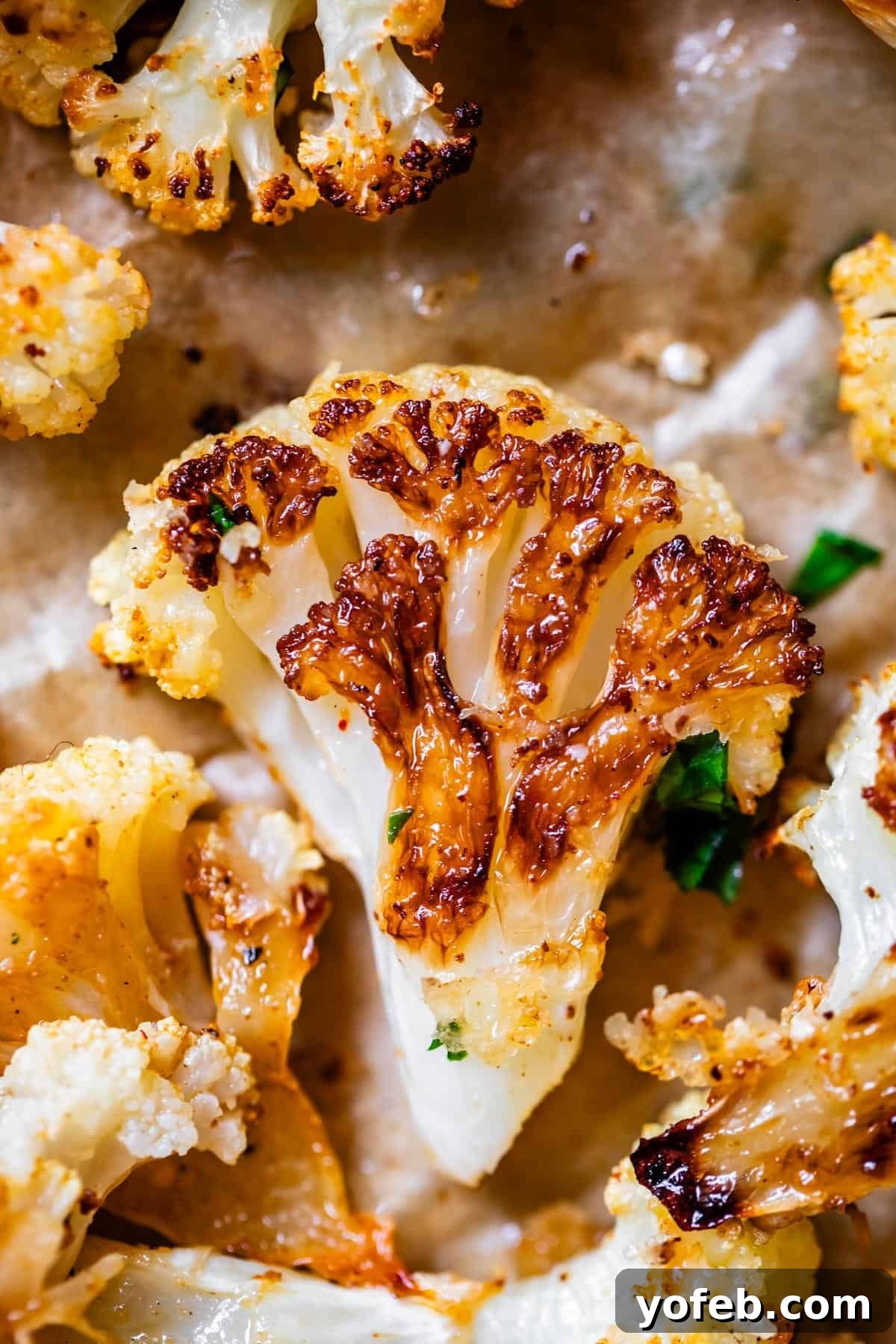 Perfectly Golden and Crispy Roasted Cauliflower 4 roasted crispy cauliflower floret on parchment paper on sheet pan.
