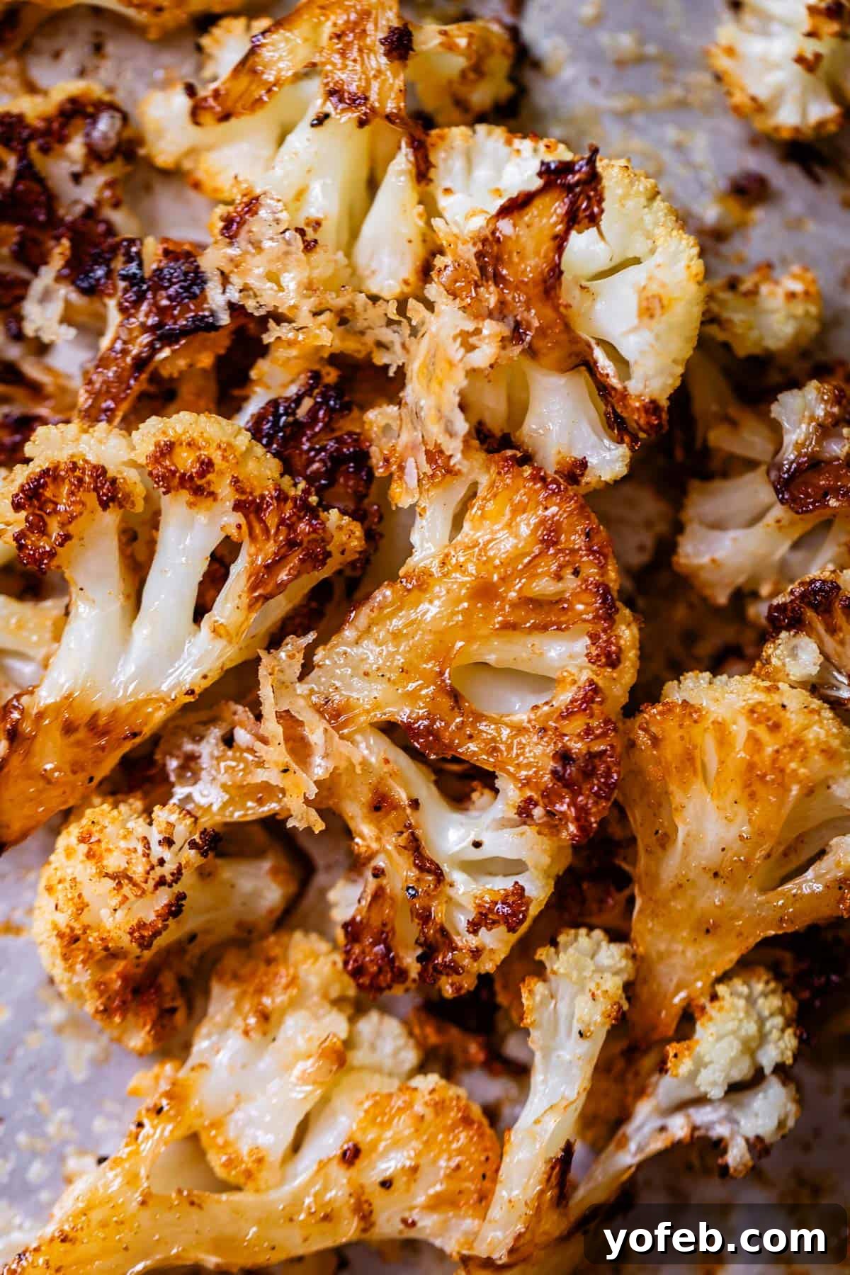 Perfectly Golden and Crispy Roasted Cauliflower 6 cheese crusted golden roasted cauliflower florets on a sheet pan.