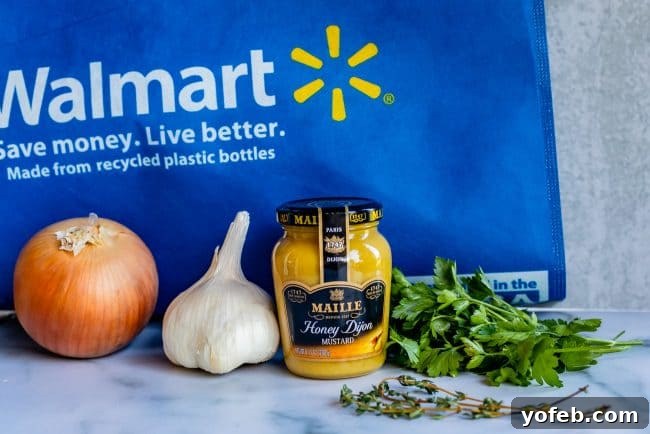 Essential Ingredients for Honey Dijon Lamb Rub Fresh ingredients laid out on a kitchen counter: red onions, garlic cloves, dried herbs, a jar of honey Dijon mustard, and a grocery bag.