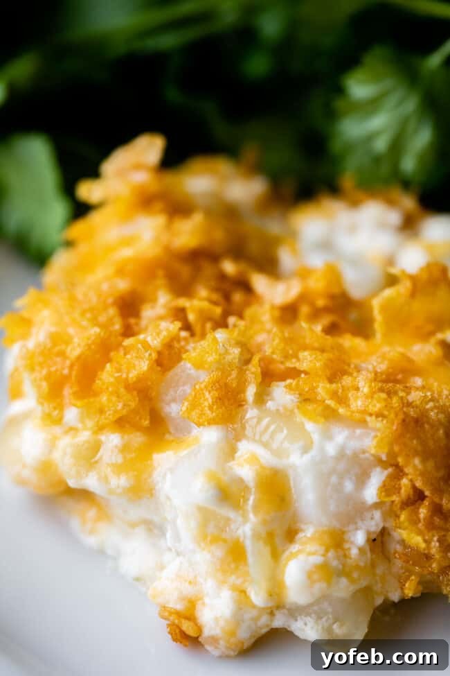 Funeral Potatoes (Cheesy Potato Casserole) from The Food Charlatan. If you haven't heard of this side dish, you will love it! Potatoes mixed with sour cream, butter, white sauce (or a can of soup - I include instructions for both), and tons of cheddar cheese, then baked to perfection with a crunchy corn flake topping. It doesn't get any better for holidays! #potatoes #withhashbrowns #easy #casserole #baked #cornflakes #fromscratch #withcornflakes #inoven #soup #homemade #quick #best close up shot of cheesy hashbrown potatoes on a plate with parsley.