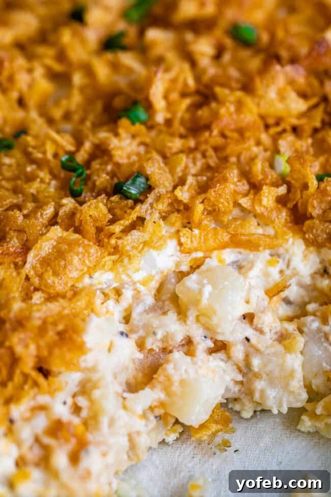 Funeral Potatoes (Cheesy Potato Casserole) from The Food Charlatan. If you haven't heard of this side dish, you will love it! Potatoes mixed with sour cream, butter, white sauce (or a can of soup - I include instructions for both), and tons of cheddar cheese, then baked to perfection with a crunchy corn flake topping. It doesn't get any better for holidays! #potatoes #withhashbrowns #easy #casserole #baked #cornflakes #fromscratch #withcornflakes #inoven #soup #homemade #quick #best cheesy potatoes topped with corn flakes and parsley.
