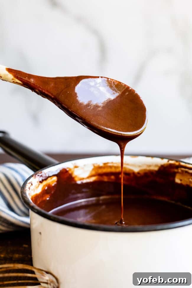 Easy Homemade Chocolate Sauce 5 Homemade chocolate sauce, thick and luxurious, slowly drips off a spoon, highlighting its smooth texture.
