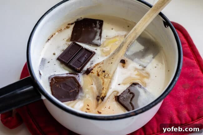 Easy Homemade Chocolate Sauce 7 Ingredients for hot fudge sauce being stirred in a saucepan with a wooden spoon.