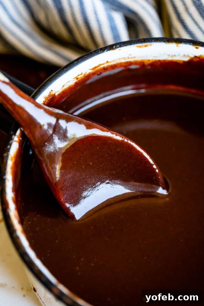 Easy Homemade Chocolate Sauce 8 A pot brimming with rich, dark chocolate sauce, a spoon resting on the side, ready for tasting.