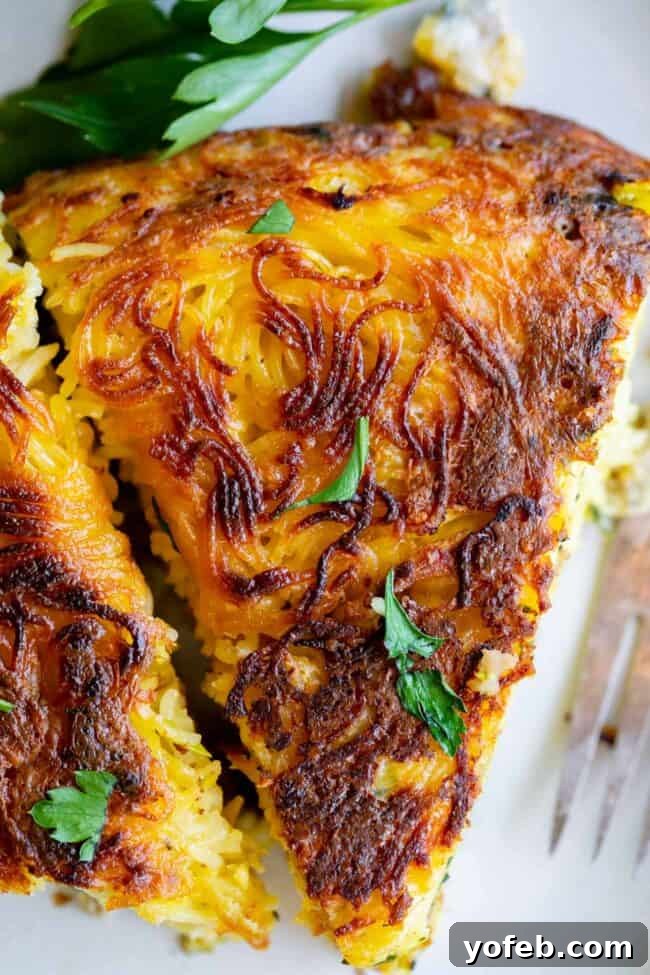 Easy 30-Minute Pasta Frittata with Sausage and Parmesan from The Food Charlatan. This dinner is done in 30 minutes and is so easy! The best part is that it uses mostly pantry ingredients (and sausage that you can freeze) so it's a good one to make when you haven't been shopping in a while! Swap out the veggies for whatever you have, and use leftover pasta if you have it! #leftoverspaghetti #recipes #dinners #eggs #cheese #Meals #brunch #dishes #breakfastrecipes #leftover #oliveoil #vegetables pasta frittata - an overhead shot of the pasta frittata, showcasing the golden-brown crust and inviting blend of ingredients