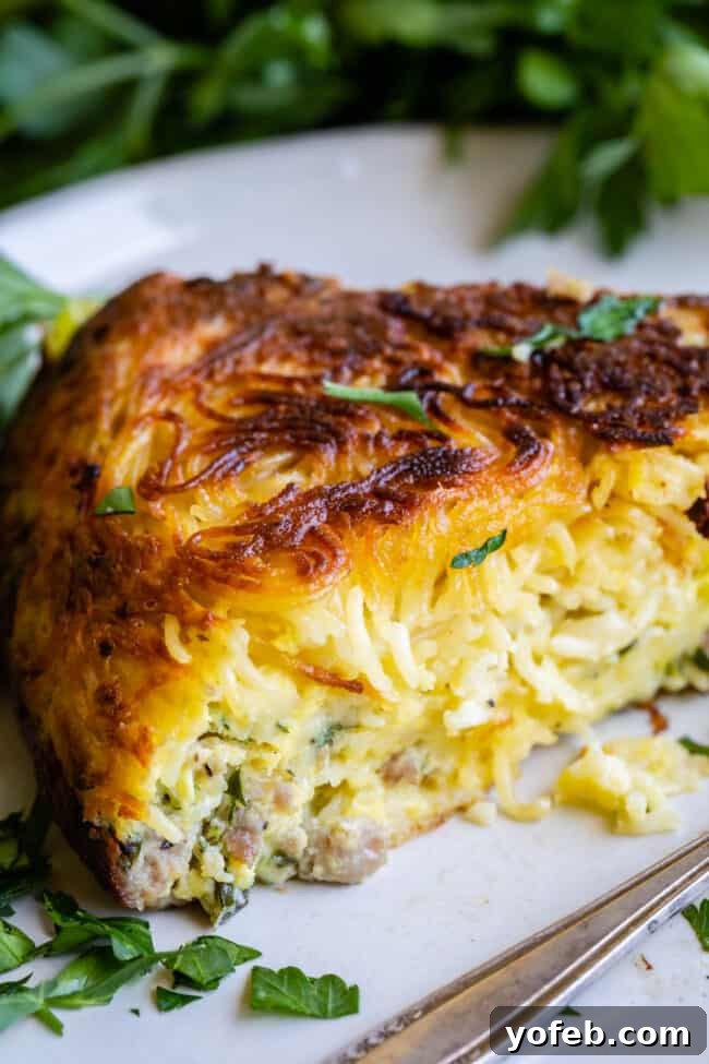 Easy 30-Minute Pasta Frittata with Sausage and Parmesan from The Food Charlatan. This dinner is done in 30 minutes and is so easy! The best part is that it uses mostly pantry ingredients (and sausage that you can freeze) so it's a good one to make when you haven't been shopping in a while! Swap out the veggies for whatever you have, and use leftover pasta if you have it! #leftoverspaghetti #recipes #dinners #eggs #cheese #Meals #brunch #dishes #breakfastrecipes #leftover #oliveoil #vegetables pasta frittata - a wide shot of the cooked frittata in a nonstick skillet, ready to be served