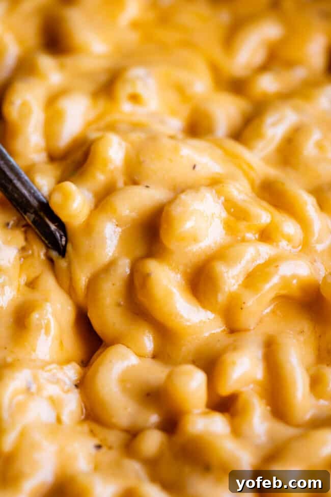 Close-up of the best slow cooker mac and cheese with a spoon digging in, revealing creamy, melted cheese and tender pasta.