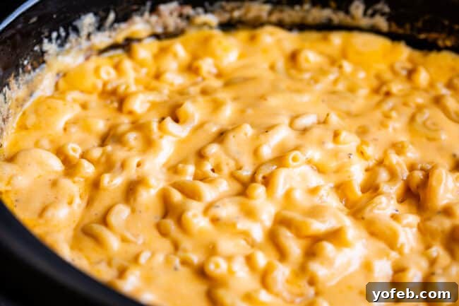 A side shot revealing the rich, creamy texture of mac and cheese cooking perfectly in a slow cooker.