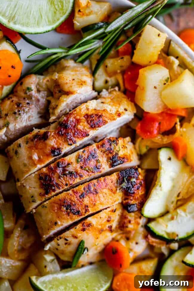 Sheet Pan Rosemary Lime Chicken and Veggies Close-up of baked rosemary lime chicken and mixed vegetables on a sheet pan, ready to serve.