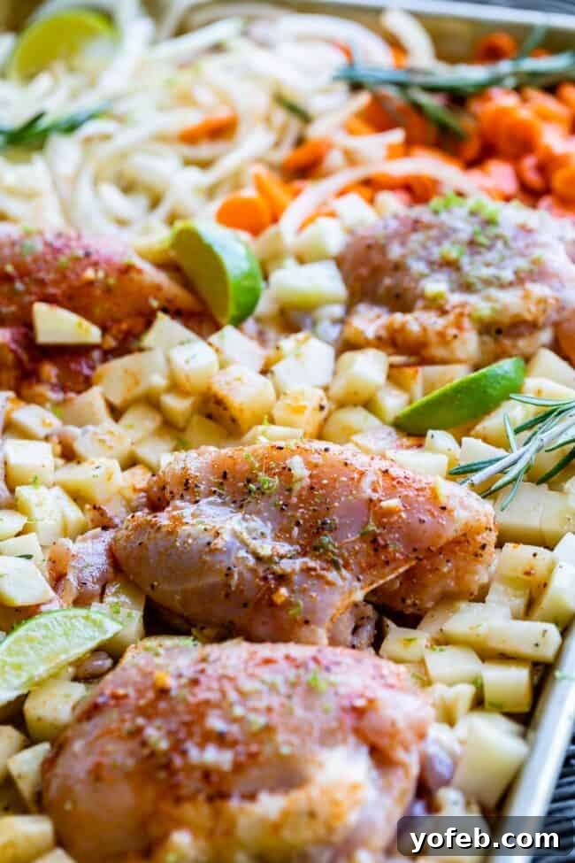 Sheet Pan Rosemary Lime Chicken and Veggies Succulent rosemary chicken thighs perfectly browned and nestled among colorful roasted vegetables on a baking sheet.