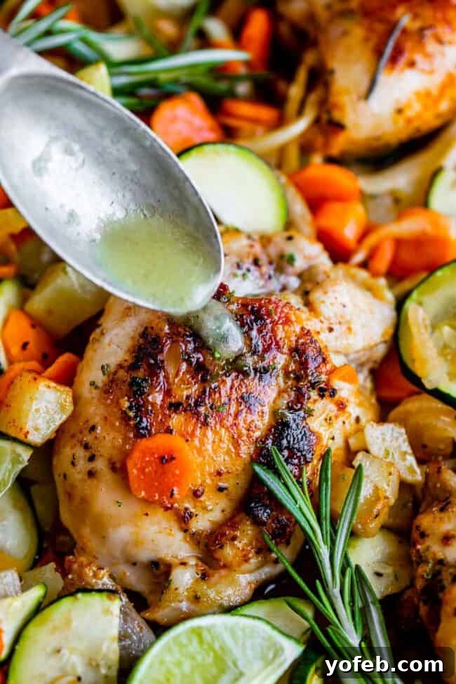 Sheet Pan Rosemary Lime Chicken and Veggies A top-down view of roasted chicken thighs seasoned with rosemary, surrounded by lime slices and baked vegetables.