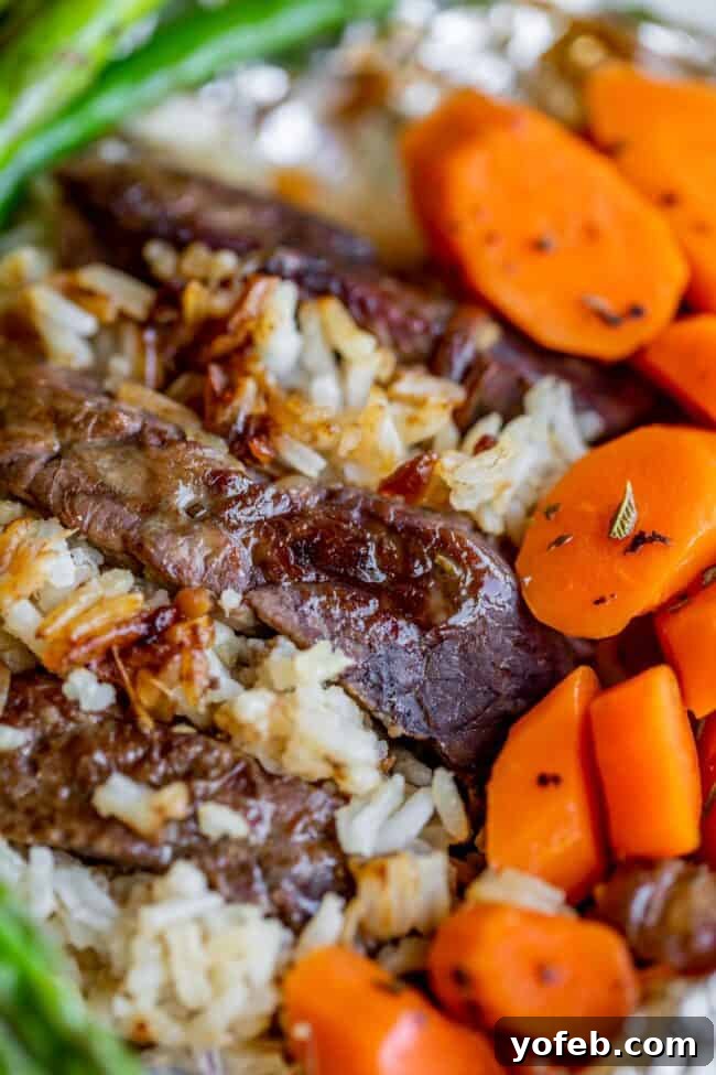 Ultimate Campfire Steak Bundles 3 Close-up of a hobo dinner featuring sliced beef, white rice, and cooked carrot rounds, garnished with green vegetable stalks in the background. The meal looks tender and freshly prepared.