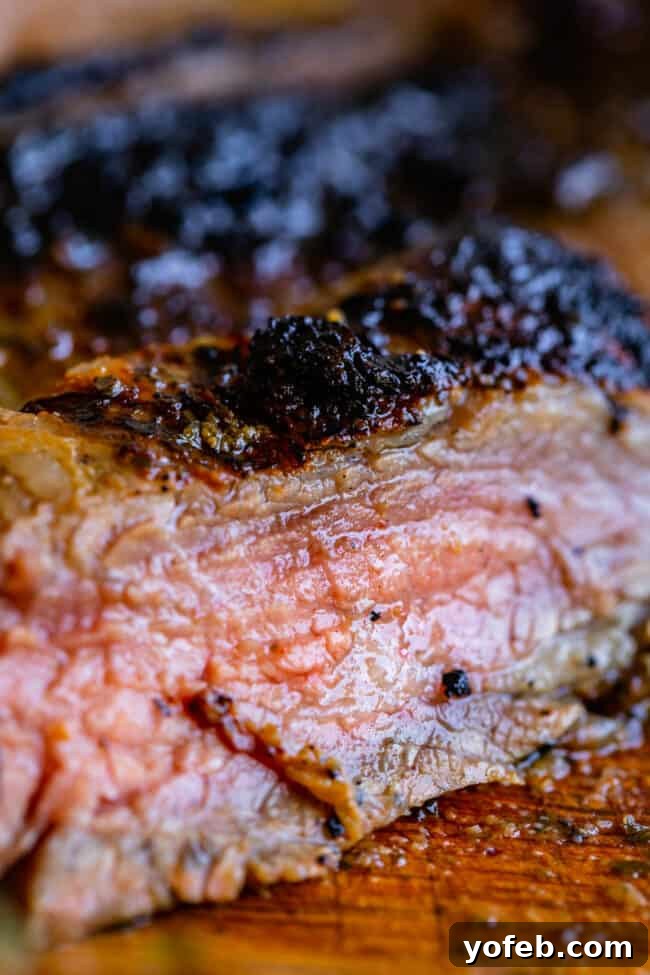 How to Cook Flank Steak (Grilled or Oven Broiled) Perfectly cooked, juicy flank steak, thinly sliced on a wooden cutting board, ready to be served.