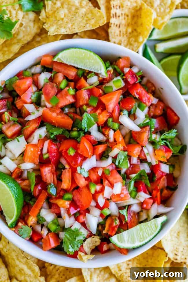 How to Make Authentic Pico de Gallo from The Food Charlatan. Learn how to make the best Pico de Gallo! It's a very simple Mexican salsa with tomatoes, onions, jalapeno, cilantro, and lime juice. Humble ingredients come together to make one of the best appetizers of all time! You will never look at tacos the same after topping them with this magical stuff. #picodegallo #salsa #Mexican #cold #fresh #appetizer #dip #forparties #easy #recipe #receta #authentic #best #homemade #restaurant #picodegalo pico de gallo in a white bowl with lime wedges and tortilla chips. A bright, fresh bowl of pico de gallo, garnished with vibrant lime wedges and served alongside crispy tortilla chips, perfect for dipping.