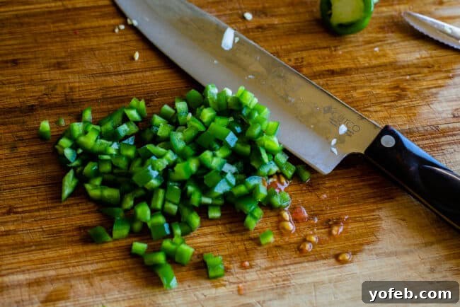 How to Make Authentic Pico de Gallo from The Food Charlatan. Learn how to make the best Pico de Gallo! It's a very simple Mexican salsa with tomatoes, onions, jalapeno, cilantro, and lime juice. Humble ingredients come together to make one of the best appetizers of all time! You will never look at tacos the same after topping them with this magical stuff. #picodegallo #salsa #Mexican #cold #fresh #appetizer #dip #forparties #easy #recipe #receta #authentic #best #homemade #restaurant #picodegalo finely chopped jalapenos for pico de gallo on a wooden cutting board. Finely chopped jalapeños on a wooden cutting board, ready to add a kick to the pico de gallo.