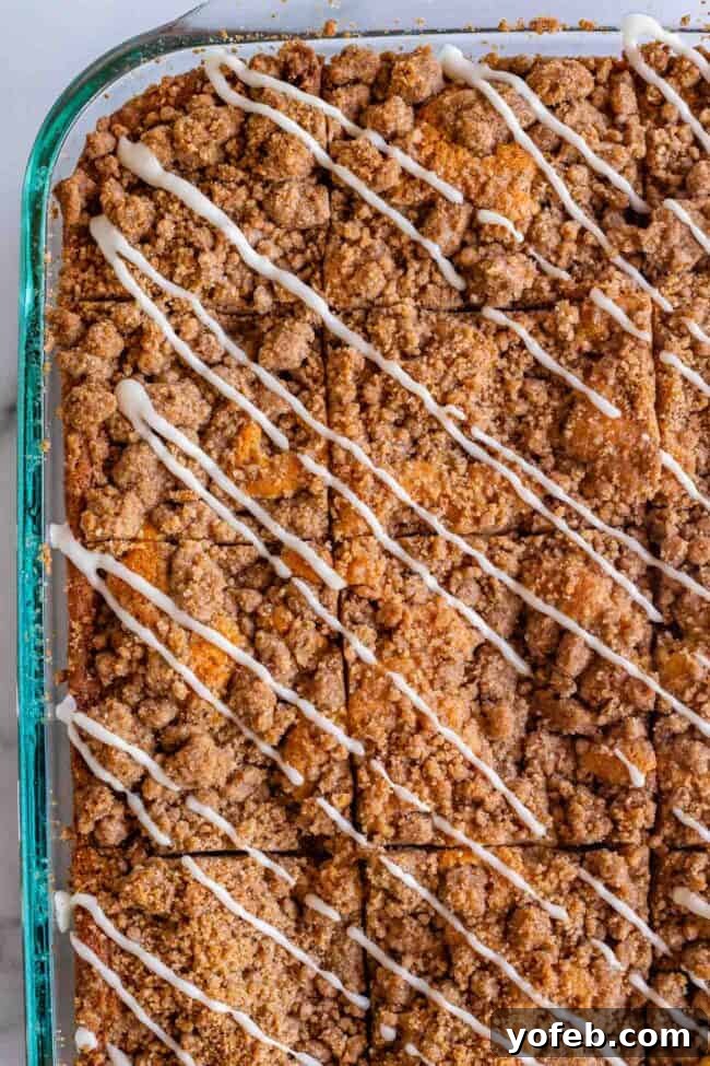 Sour Cream Coffee Cake, with a Ridiculous Amount of Streusel from The Food Charlatan. This is my FAVORITE recipe for Sour Cream Coffee Cake! My main complaint with Coffee Cake is that there is usually too much cake, not enough streusel. This recipe gives you the max amount of streusel without ruining the light fluffiness of the cake! A vanilla drizzle finishes it off! #coffeecake #sourcream #icing #frosting #drizzle #easy #recipes #cinnamon #streusel #sourcream #crumb #crumble #moist #breakfast Streusel coffee cake in a 9x13 inch pan with diagonal drizzles of vanilla icing.