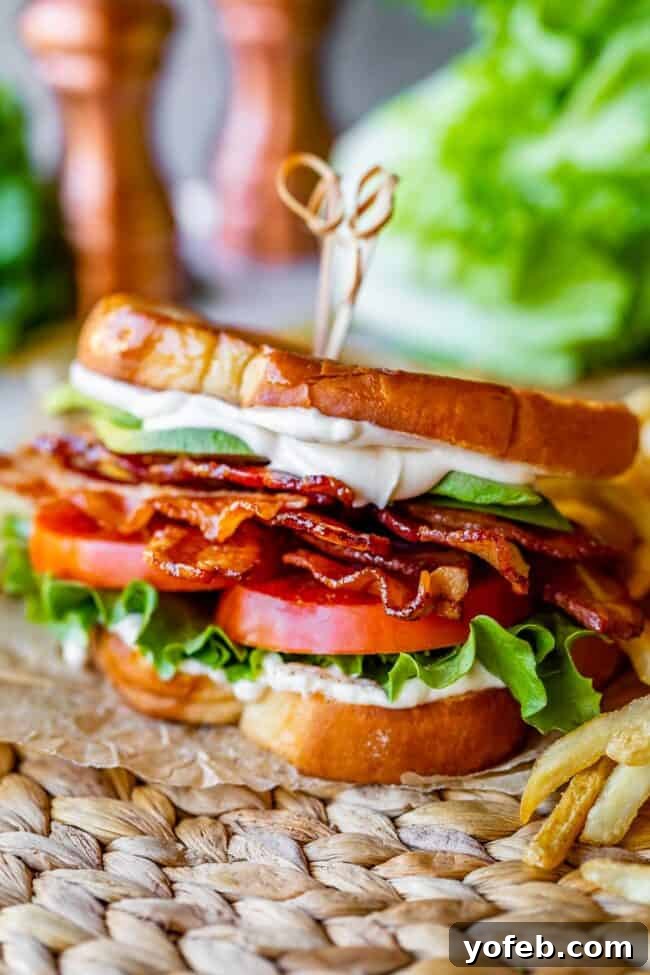 Crafting the Flawless BLT 16 blt sandwich with french fries, on parchment paper with lettuce and salt and pepper shakers in the background
