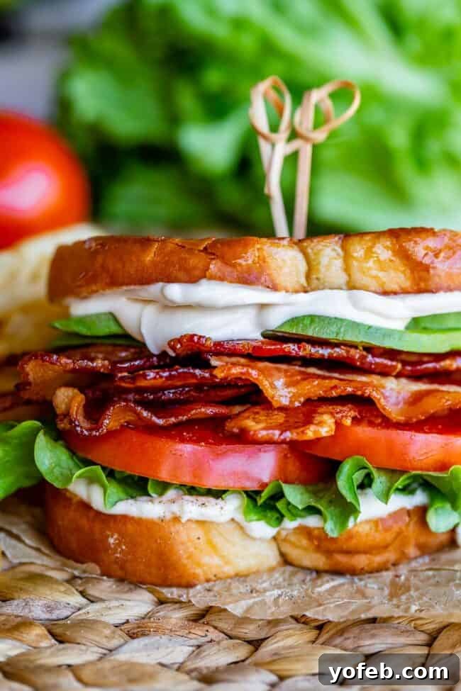 Crafting the Flawless BLT 3 avocado BLT with toothpicks on top, on parchment paper with lettuce in the background
