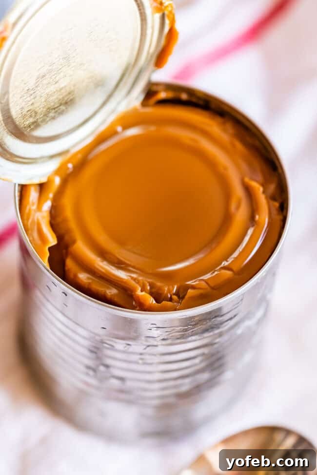 An open can revealing the smooth, golden-brown dulce de leche inside, ready to be stirred.