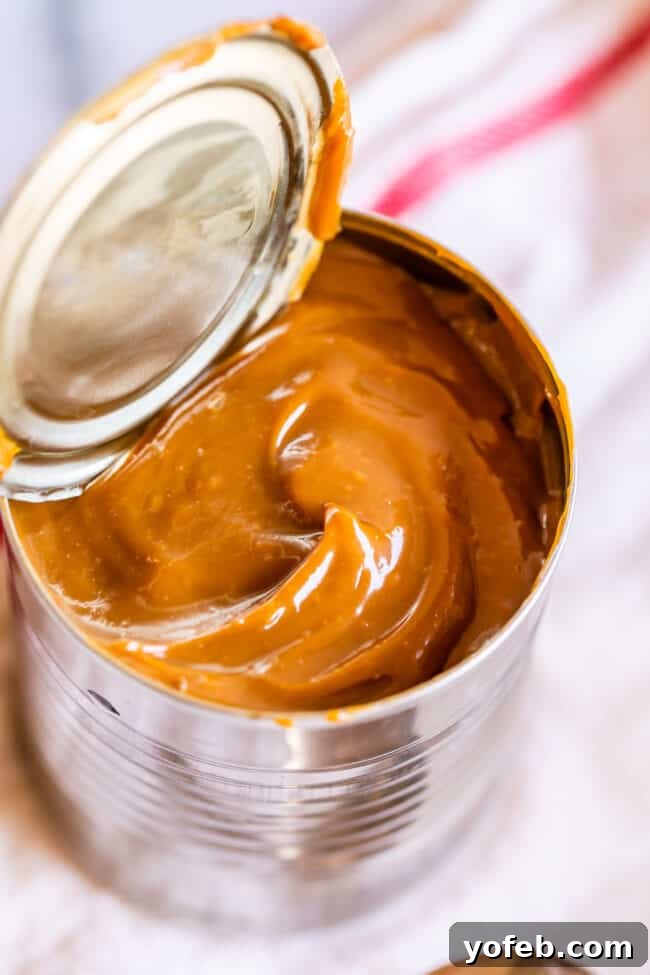 A can of sweetened condensed milk transformed into rich, creamy dulce de leche, with a spoon ready for tasting.