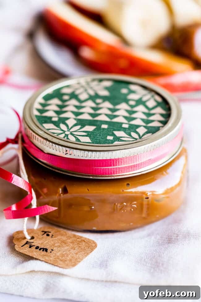 A charming glass jar of dulce de leche adorned with festive Christmas wrapping paper on the lid and a decorative gift tag, ready for gifting.