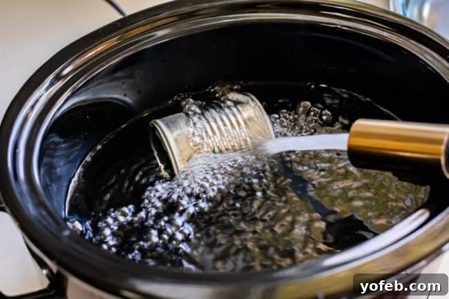 A can of sweetened condensed milk submerged in water inside a slow cooker, ready to be cooked into dulce de leche.