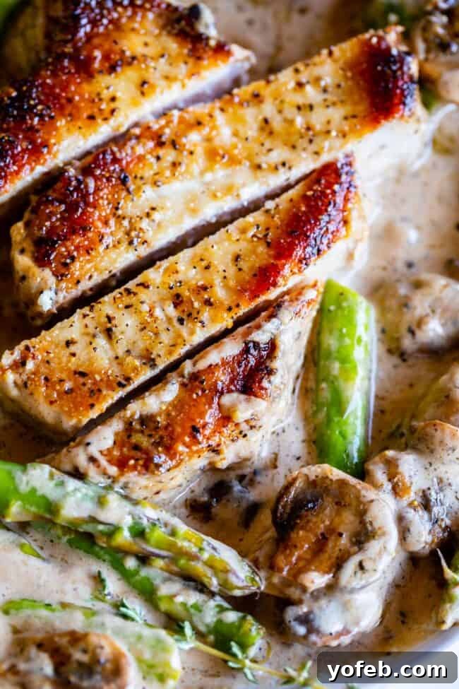 Pan-Seared Pork Chops with Velvety Mushroom Sauce 4 Succulent slices of pan-seared pork chop, layered with tender mushrooms and asparagus, coated in a luscious, creamy pan gravy, invitingly arranged on a serving plate.