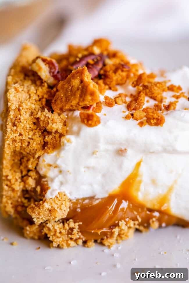 Dulce de Leche Pie with Pecan-Graham Crumble Topping A close-up of a completed Dulce de Leche Cream Pie, adorned with a generous sprinkle of golden pecan-graham crumble over fluffy whipped cream.