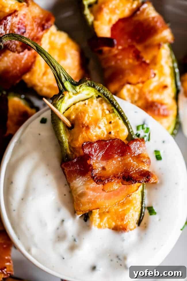 10 Quick Holiday Appetizer Recipes 3 A bacon-wrapped, cheese-stuffed jalapeño popper is dipped into creamy white ranch dressing, with other poppers in the background—perfect as holiday appetizers.