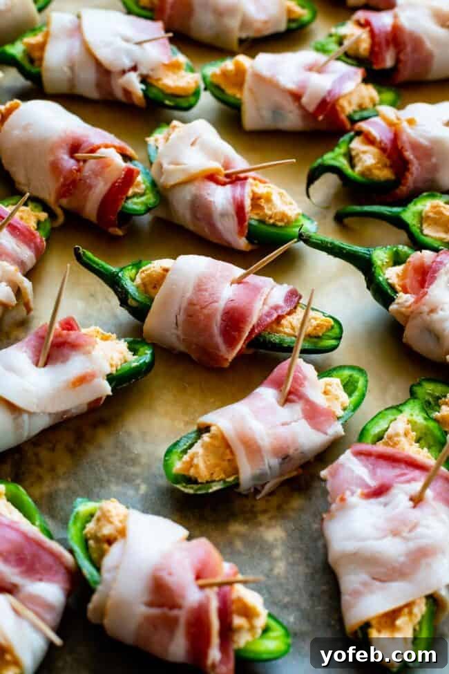 Unbaked Bacon Wrapped Jalapeño Poppers A baking sheet filled with unbaked bacon-wrapped jalapeño poppers, each secured with a toothpick, ready for cooking.