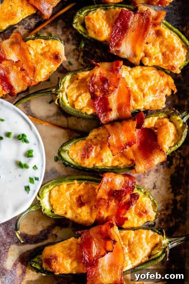 Bacon Wrapped Jalapeño Poppers with Ranch Dip A vibrant display of bacon-wrapped jalapeño poppers arranged around a small bowl of ranch dressing, ready for serving.