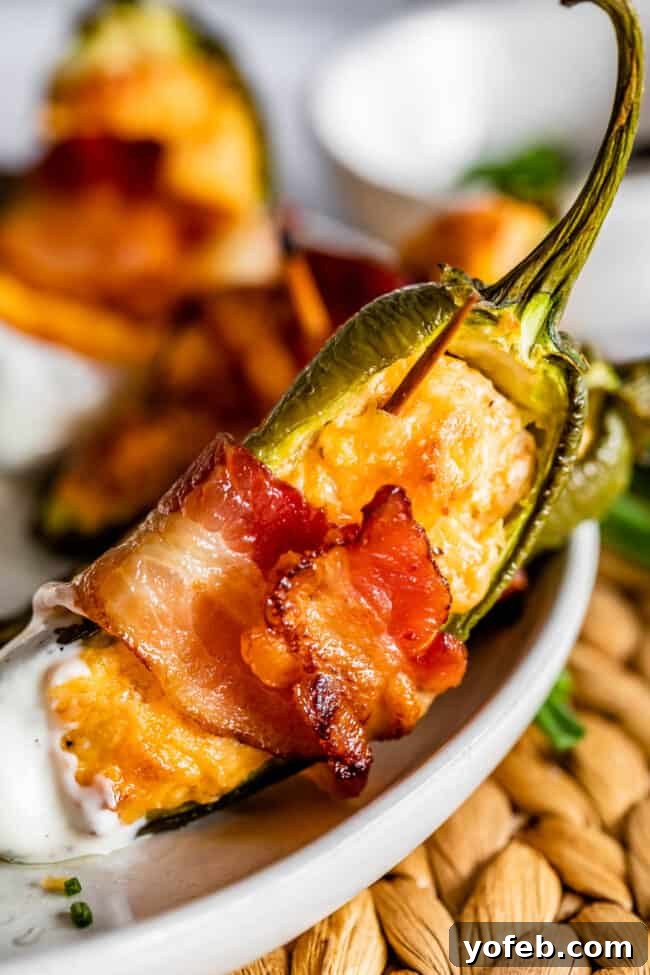 A Delicious Bacon Wrapped Jalapeño Popper A single, perfectly cooked bacon-wrapped jalapeño popper, showcasing its crispy bacon exterior and creamy filling.