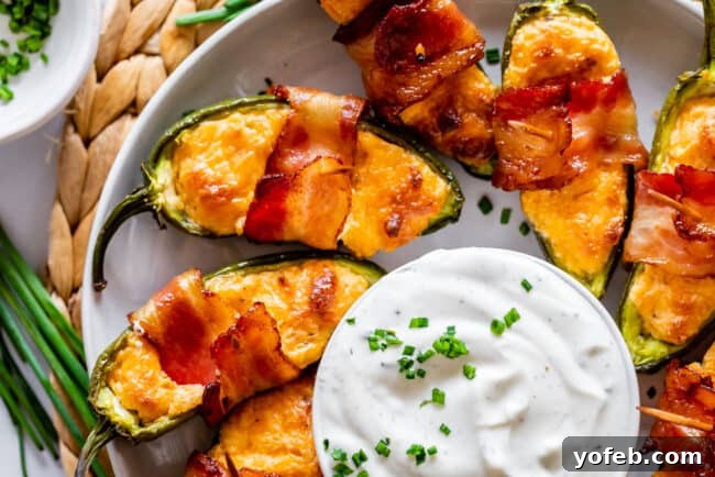 Jalapeño Poppers with Ranch Dip A beautiful arrangement of golden-brown bacon-wrapped jalapeño poppers surrounding a bowl of creamy ranch dressing, ready to be enjoyed.