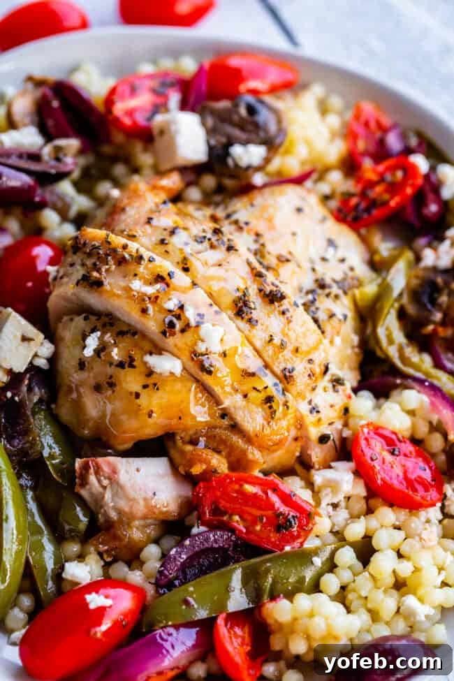 One-Pan Zesty Greek Chicken and Roasted Vegetables 8 A delectable shot of the finished oven baked Greek chicken, garnished with Kalamata olives and crumbled feta cheese, served with couscous.