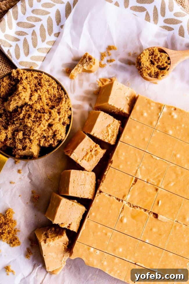 Easy Penuche Fudge Recipe (Brown Sugar Fudge) from The Food Charlatan. An easy recipe for Penuche Fudge! It only takes a few minutes to put together this easy brown sugar fudge. It's similar to my favorite Chocolate Fudge recipe, but instead uses brown sugar and white chocolate. The texture of this fudge is where it's at! #oldfashioned #penuche #fudge #whitechocolate #brownsugar #candy #Christmas #holidays #praline #Easy #recipe #best #withmarshmallowfluff #withevaporatedmilk #pecans #creamy A measuring cup brimming with rich brown sugar stands beside neat squares of Penuche Fudge, highlighting the key ingredient and the finished product.