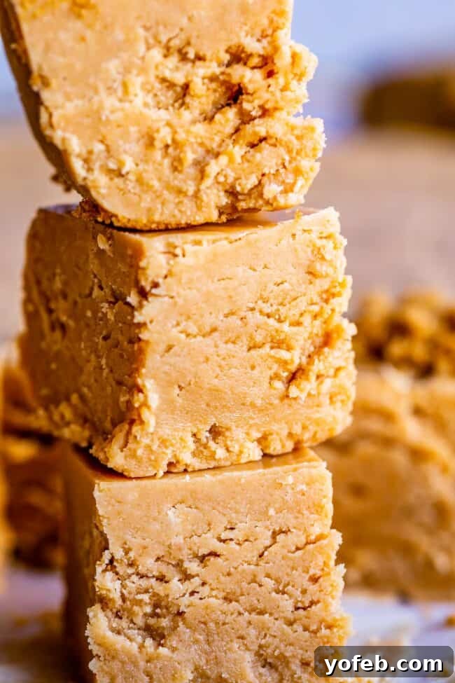 Easy Penuche Fudge Recipe (Brown Sugar Fudge) from The Food Charlatan. An easy recipe for Penuche Fudge! It only takes a few minutes to put together this easy brown sugar fudge. It's similar to my favorite Chocolate Fudge recipe, but instead uses brown sugar and white chocolate. The texture of this fudge is where it's at! #oldfashioned #penuche #fudge #whitechocolate #brownsugar #candy #Christmas #holidays #praline #Easy #recipe #best #withmarshmallowfluff #withevaporatedmilk #pecans #creamy A delectable stack of rich brown sugar fudge pieces, showcasing their thick, creamy consistency and inviting texture.