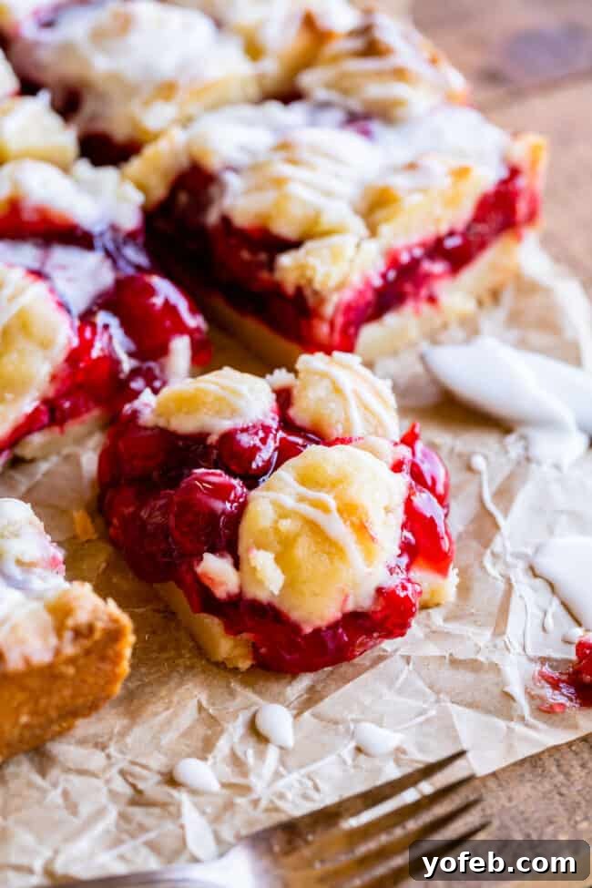 Cherry pie bars cooling on a wire rack, with a rich vanilla glaze drizzled generously over the top.