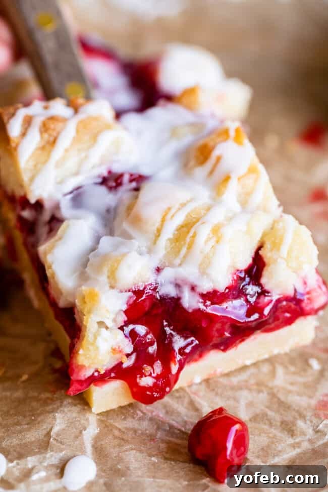 Close-up of a perfectly baked cherry pie bar, showcasing the crumbly shortbread topping and vibrant red cherry filling.